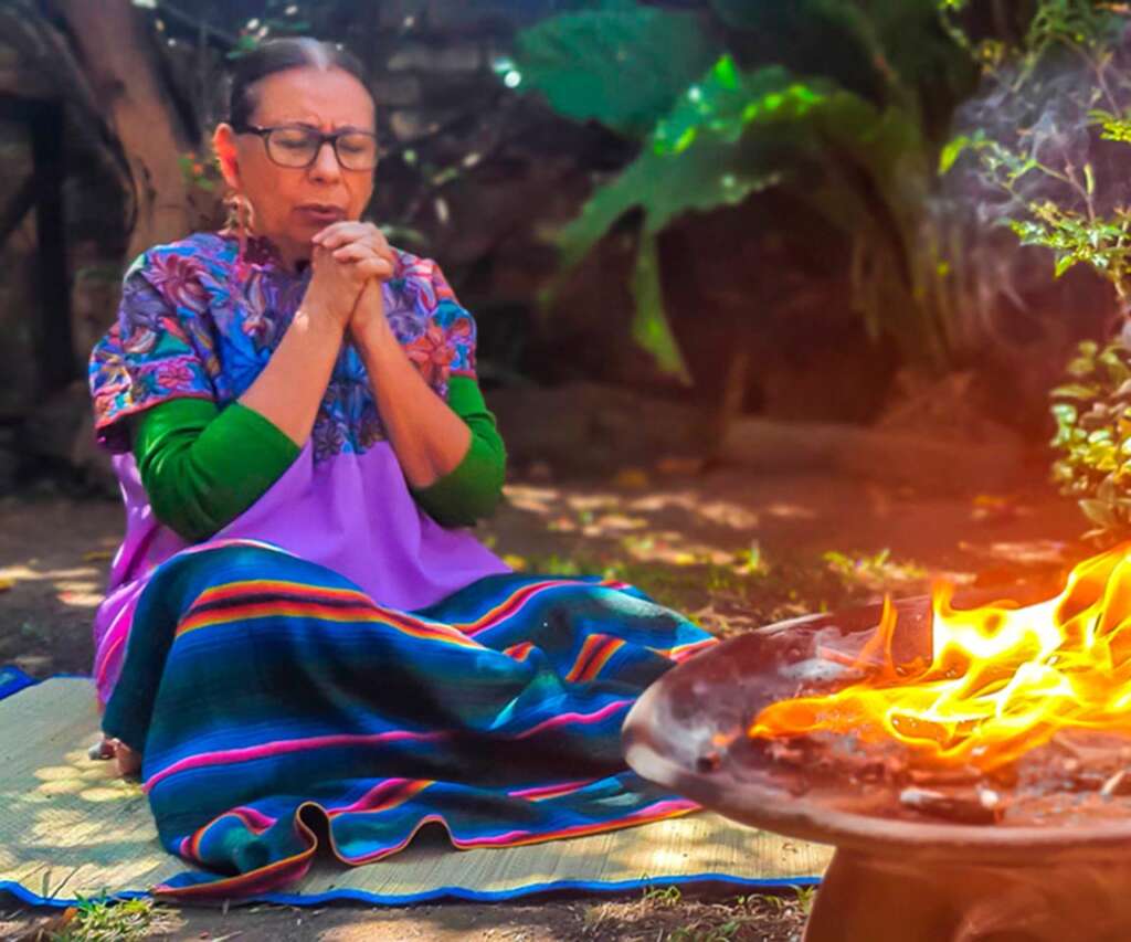 Nana Tzununja Maria Eugenia Aguilar, is a mayan ajqij and indigenous healer and spiritual guide. She is in front of the sacred fire praying. 